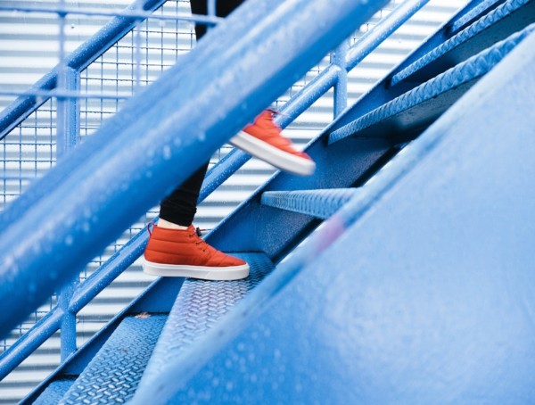 Frau läuft eine Treppe hoch, es ist nur eine Nahaufnahme ihrer roten Senkers zu sehen