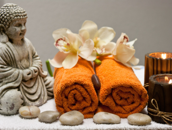 Nahaufnahme von eine Buddha-Figur mit eingerollten Handtüchern, Kerzen und kleinen Steinen