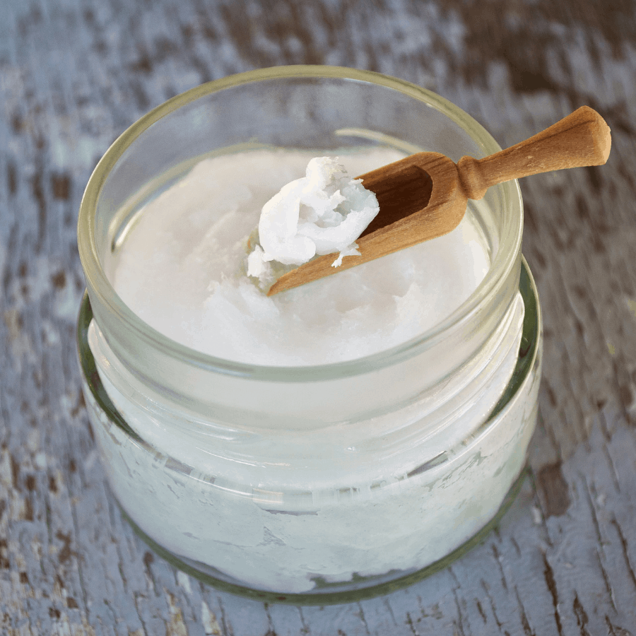 Nahaufnahme eines Glas mit Kokosöl und Holzlöffel