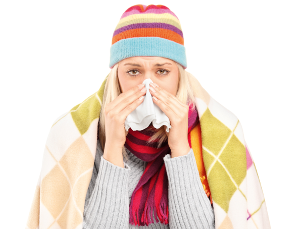 erkältete Frau mit Winteroutfit blickt in die Kamera und putzt sich die Nase