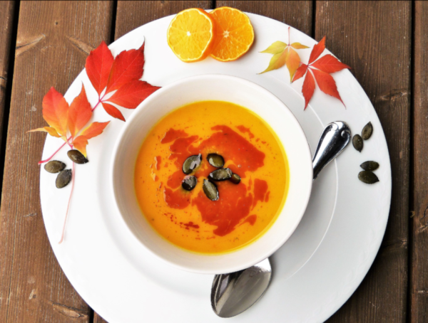 Ein Teller Kürbissuppe mit herbstlicher Deko am Tellerrand