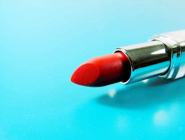 roter Lippenstift in silberner Hülse auf hellblauem Untergrund