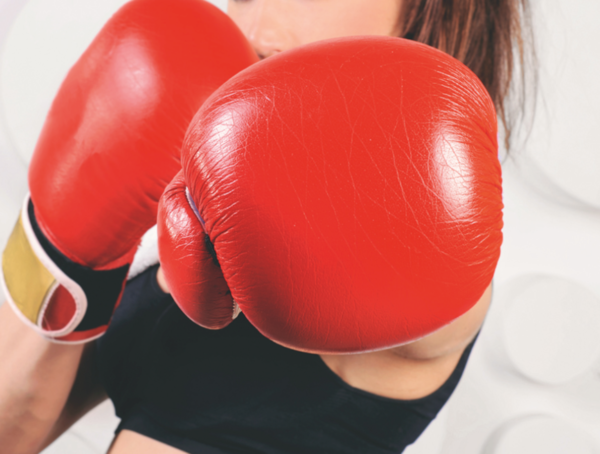 Nahaufnahme von Boxhandschuhen, die eine Frau in Sportkleidung trägt