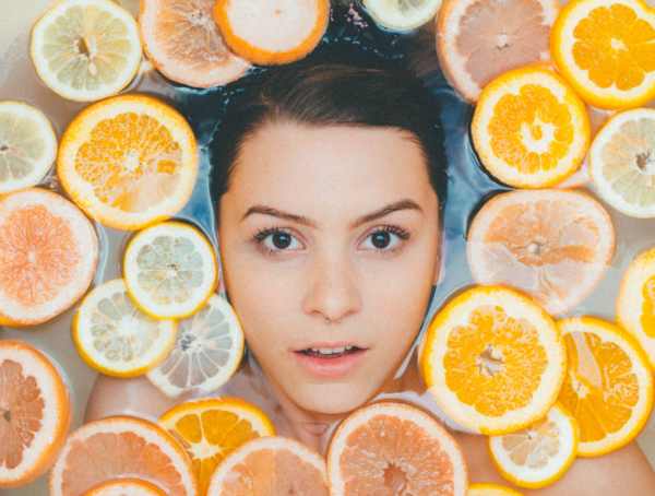 Eine junge Frau nimmt ein Zitrusbad mit Orangen- und Zitronenscheiben