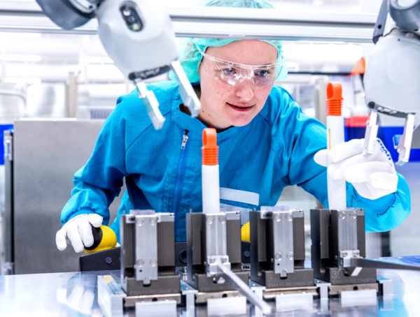 Frau mit Schutzbrille und Schutzkleidung bei der Penfertigung des SoloStar von Sanofi