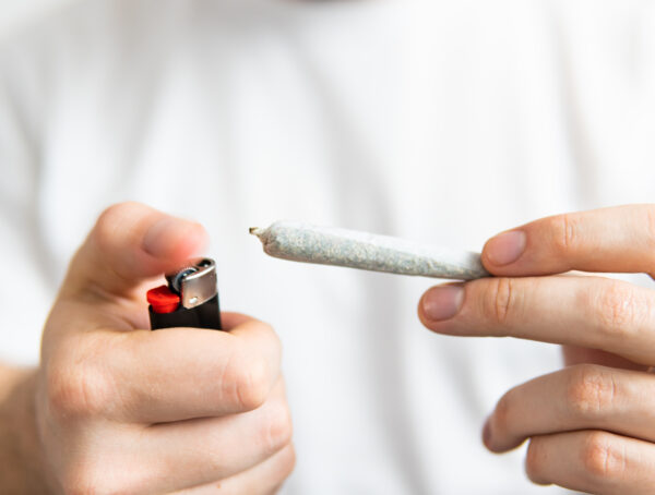 Eine Hand hält einen Joint und in der anderen ein Feuerzeug.