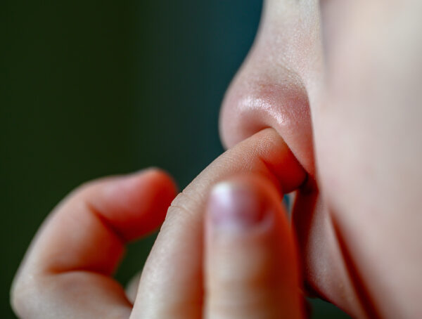 Eine Person bohrt mit dem Finger in der Nase.