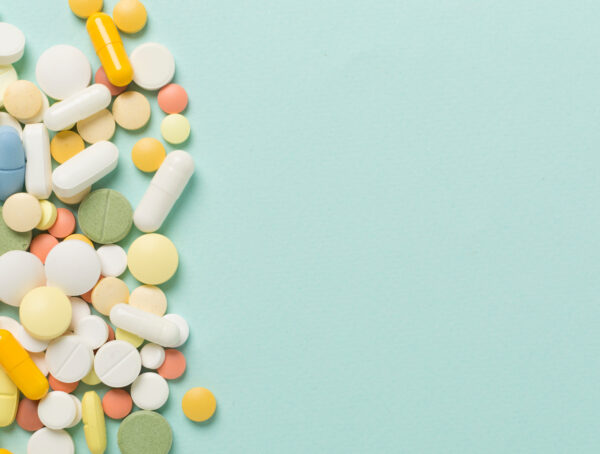 Tabletten und Kapseln in verschiedenen Farben und Formen auf mintgrünem Hintergrund