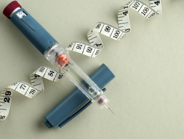 Ein Maßband und ein geöffneter Fertigpen einer Abnehmspritze.