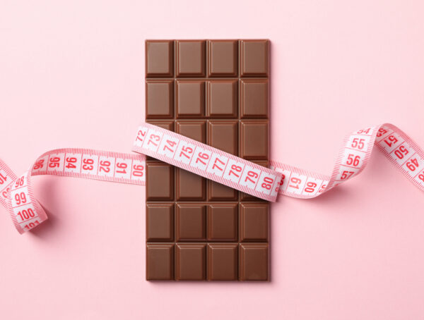 Tafel Vollmilchschokolade, die vo einem Maßband umwickelt ist.