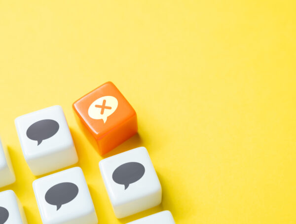 Weiße Würfel mit Sprechblasen-Symbolen darauf, daneben ein roter Würfel mit einem X darauf.