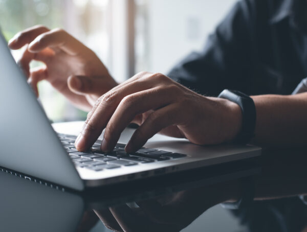 Zwei Hände tippen auf der Tastatur von einem Laptop