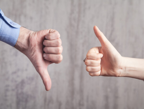 Hand mit Daumen nach unten und eine andere Hand mit Daumen nach oben
