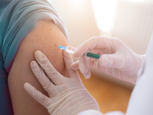 In einen Oberarm wird eine Spritze verabreicht.