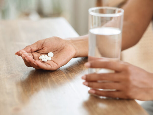 Symbolbild einer Tabletteneinnahme mit einem Glas Wasser