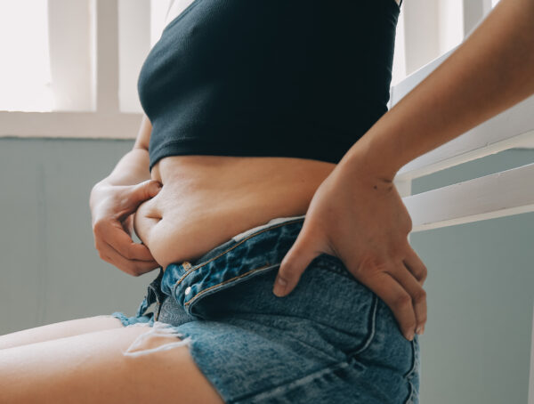 Symbolbild bei dem eine Frau mit der Hand in ihren Bauch kneift