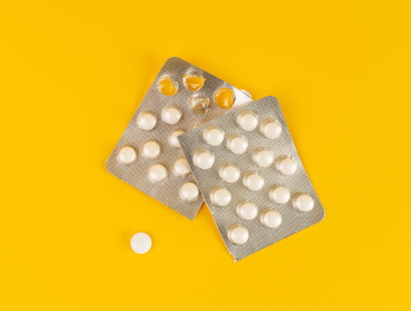 Symbolbild mit zwei silbernen Blistern mit weißen Tabletten, aus deinem davon wurde eien weiße Tablette herausgedrückt
