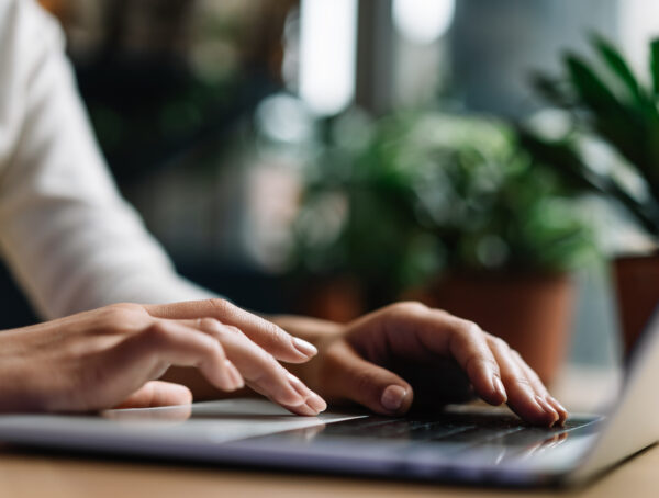 Symbolbild mit zwei Frauenhänden, die die Tastatur eines Laptops bedienen