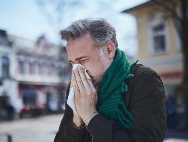 Hier noch der ALT-Text: Erkälteter Mann, der sich schnupft.