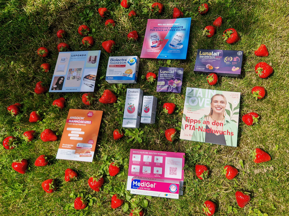 Inhalt der PTA IN LOVE-Box auf einer Wiese mit Erdbeeren