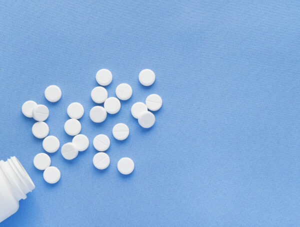 Symbolbild einer Tablettendose mit vielen Tabletten davor.