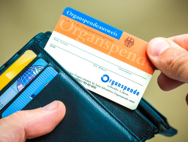Symbolbild mit einem Geldbeutel mit einem Organspendeausweis in der Hand.